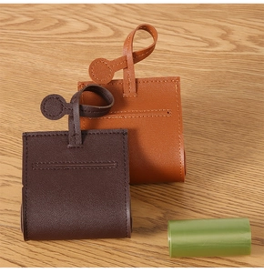 Close-up of leather dog waste bag dispensers in brown and caramel on wood background