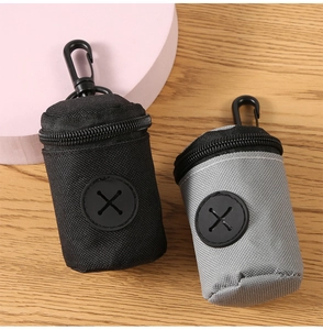 Detail of grey and black pet waste bag dispensers with hooks on wooden background