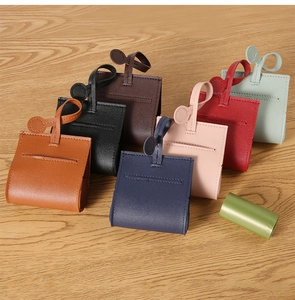 Flat lay view of various colorful leather pet waste bag dispensers on a wood table