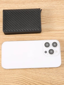Portabiglietti da visita in pelle di carbonio nera accanto a smartphone su legno