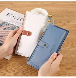 Detailed view of long zip leather wallets in blue and white held by a model over a desk