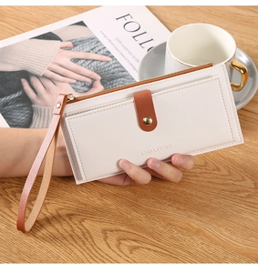 Close-up of minimalist cream long wallet with brown wristlet strap and zipper closure
