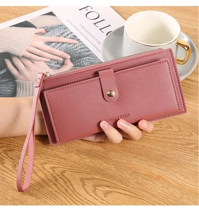 Detail of dusty pink leather long wallet showing card slots, zipper and wrist strap