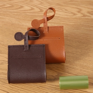 Brown leather dog waste bag dispensers in two shades on a natural wooden background