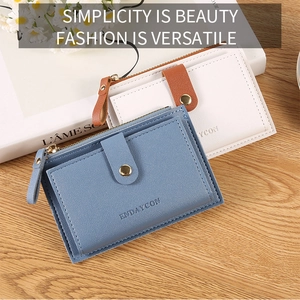 Detail of slim leather wallet showing litchi texture with gold zipper and snap button