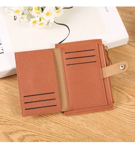 Detail view of tan litchi pattern wallet showing 6 card slots and button closure on wood