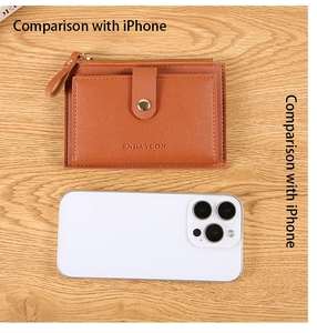 Brown leather card holder with gold hardware and multiple slots next to a smartphone