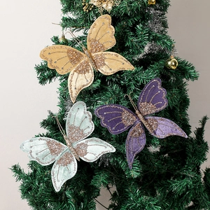 Three glittery Christmas butterfly ornaments in gold purple and blue on a green tree