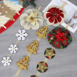 Christmas garland decoration featuring snowflakes, gold trees and red plaid flowers on wood