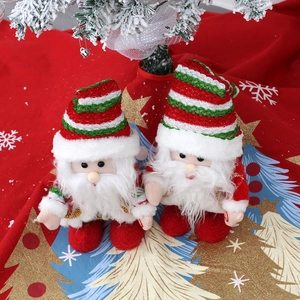 Détail de figurines du Père Noël en peluche sur un tapis rouge aux paillettes dorées