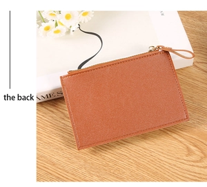 Rear view of a brown pebbled PU leather wallet with gold zipper on a wooden table
