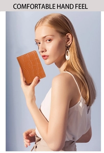 Brown crocodile pattern compact wallet with card slots and button closure in a woman's hand