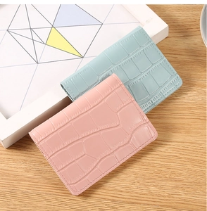 Detail of pink and light blue croc-embossed wallets on a clean wooden surface