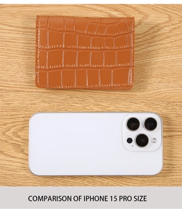 Brown crocodile embossed short wallet size comparison with iPhone 15 Pro