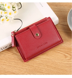 Detail of red leather card holder featuring gold zipper, buckle and embossed texture
