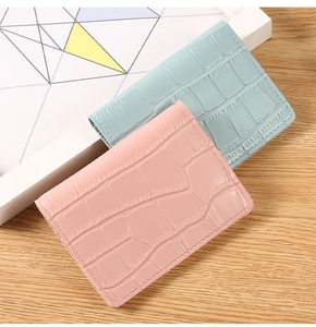 Detail of light blue and pink card holders with crocodile pattern on a wooden table