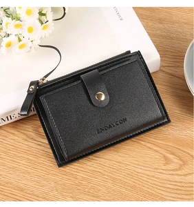 Close-up of black litchi leather wallet with golden zipper and metal buckle on wood table