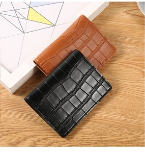 Flat lay of black and brown crocodile textured leather wallets on a wooden tabletop