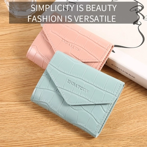 Detail of minimalist crocodile pattern small wallets in light pink and blue finishes