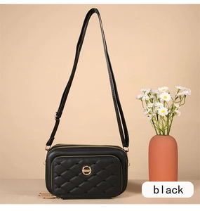 Détail d'un sac bandoulière noir matelassé avec trois compartiments zippés et fermoir doré
