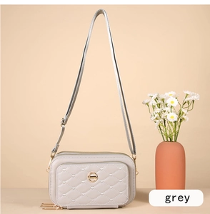 Détail du sac bandoulière gris matelassé avec surpiqûres en cœur et logo doré chic