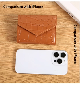 Detailed view of crocodile pattern wallet with size comparison next to a phone