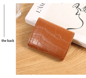 Detail view showing the back of a brown crocodile pattern card holder on a wooden table