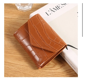 Detail shot of brown crocodile pattern card holder wallet on a minimalist wooden desk