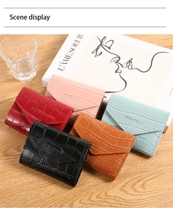 Close-up of five crocodile-embossed envelope wallets stacked on a wooden desk
