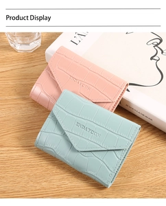Detail of pink and blue envelope wallets with crocodile embossed leather on a wooden table