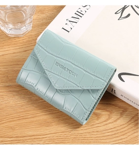 Detail of light blue crocodile embossed card wallet showing envelope flap and brand logo