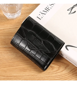 Macro shot of black crocodile embossed tri-fold wallet with ENLAYCO logo on wood surface