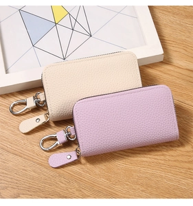 Close-up of PU leather key pouches in cream and lilac with silver metallic hardware