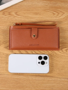 Brown leather long wallet with wristlet and zipper compartment on wood background