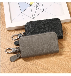 Detail view of lychee pattern PU leather key pouch with metal carabiner on wood surface