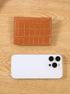 Brown crocodile texture leather wallet and card holder on wood surface with phone
