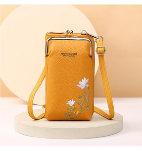 Detail of ginger yellow leather crossbody phone bag with elegant floral embroidery patterns