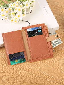 Brown faux leather short wallet with multiple card slots and snap closure on wood