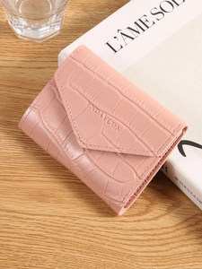 Pink faux crocodile embossed mini wallet for women on a cozy wooden desk display