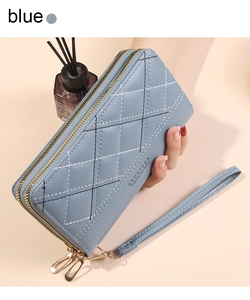 Close-up of blue quilted double-zipper wallet with gold hardware and wristlet strap