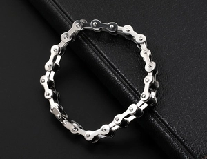 Dettaglio ravvicinato di un bracciale in acciaio argento a catena di bici su pelle