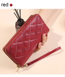 Detail view of red double-zipper wallet with diamond quilting and wristlet strap