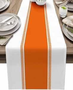 Detailed view of modern striped table runner with orange geometric patterns on wooden table