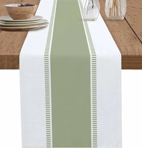 Close-up of sage green striped table runner on wooden table with ceramic dinnerware