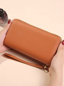 Brown long faux leather wallet with double zippers and wrist strap shown in hand