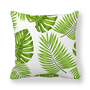 Macro detail of tropical green palm and monstera leaf print on white peach skin pillow