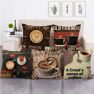 Detailed close-up of vintage coffee themed linen pillow covers on a beige sofa