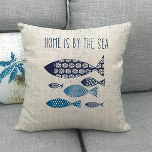 Close-up of nautical pillow cover with blue fish patterns on a grey sofa fabric