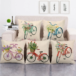 Set of five linen pillow covers with retro bicycle and floral motifs on a beige sofa