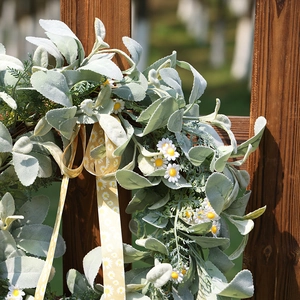 Couronne de pâquerettes et feuilles d'oreilles de lapin avec ruban jaune sur clôture